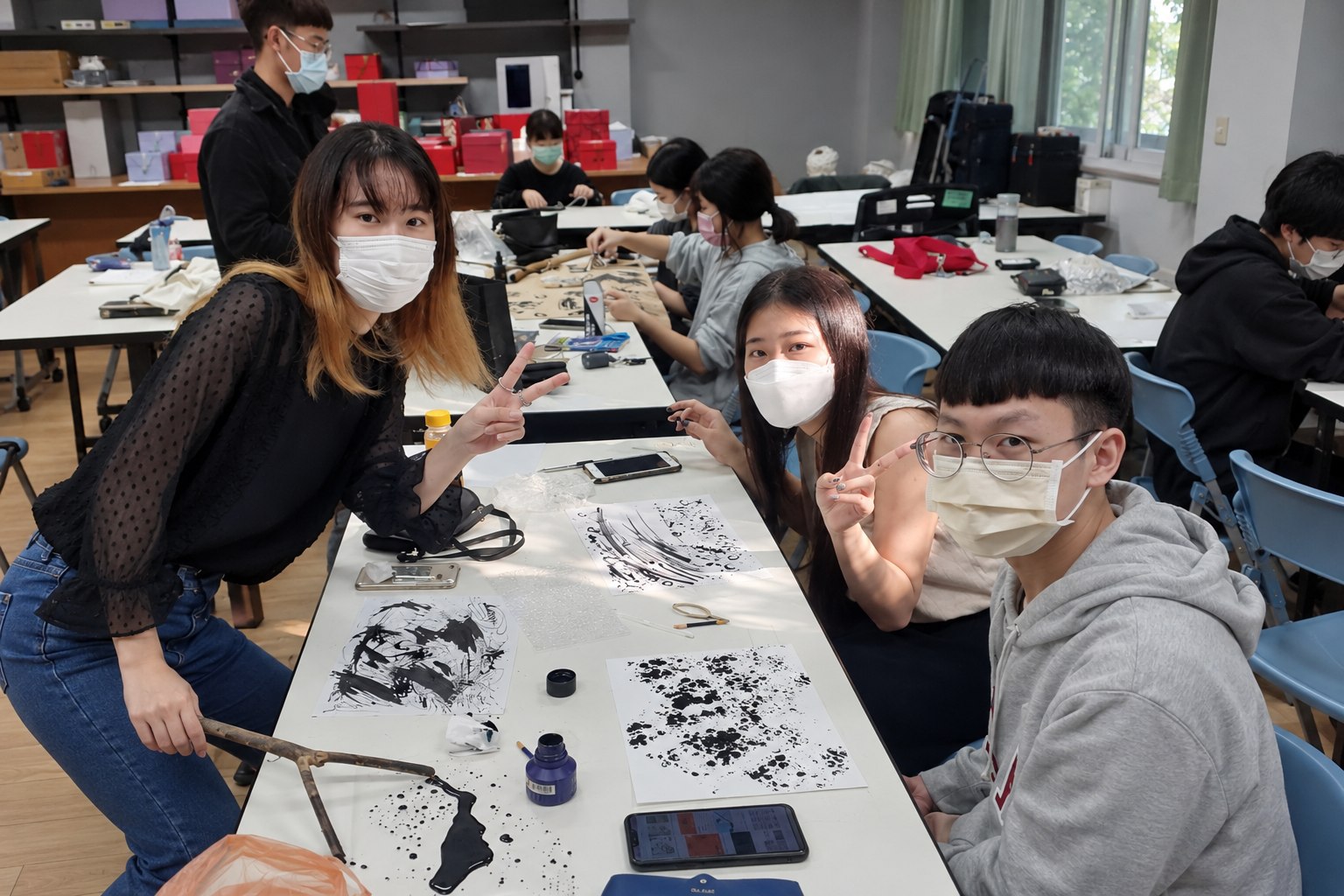 學生在課堂展示不同工具的黑色墨水筆觸,桌面前方的紙張呈現泡泡紙壓印紋理